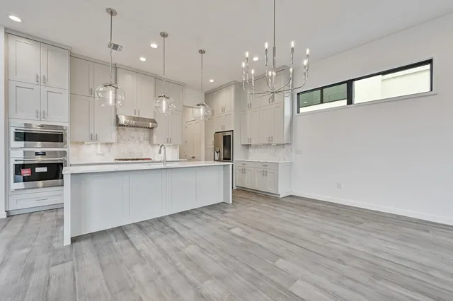a large kitchen with cabinets wooden floor and stainless steel appliances