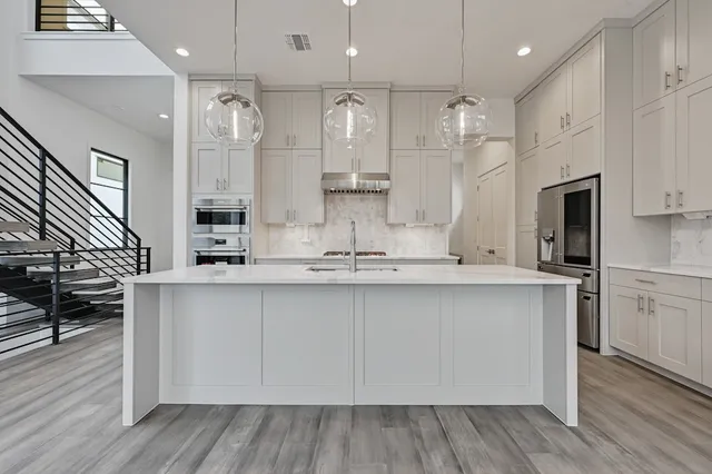 a kitchen with stainless steel appliances granite countertop a sink a stove a refrigerator and island with wooden floor