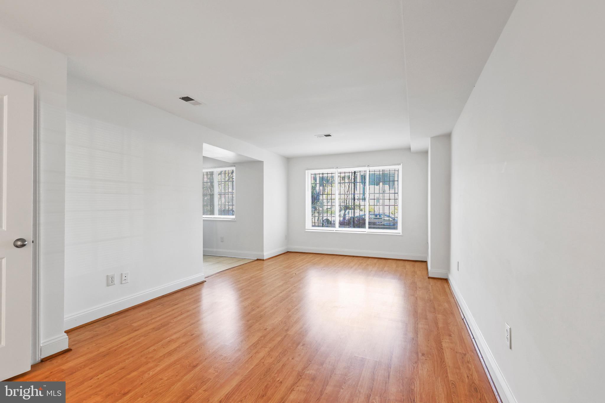 1316 Spring Road Northwest, Unit 102 Washington, DC 20010 - Photo 1 of 11 an empty room with wooden floor and windows