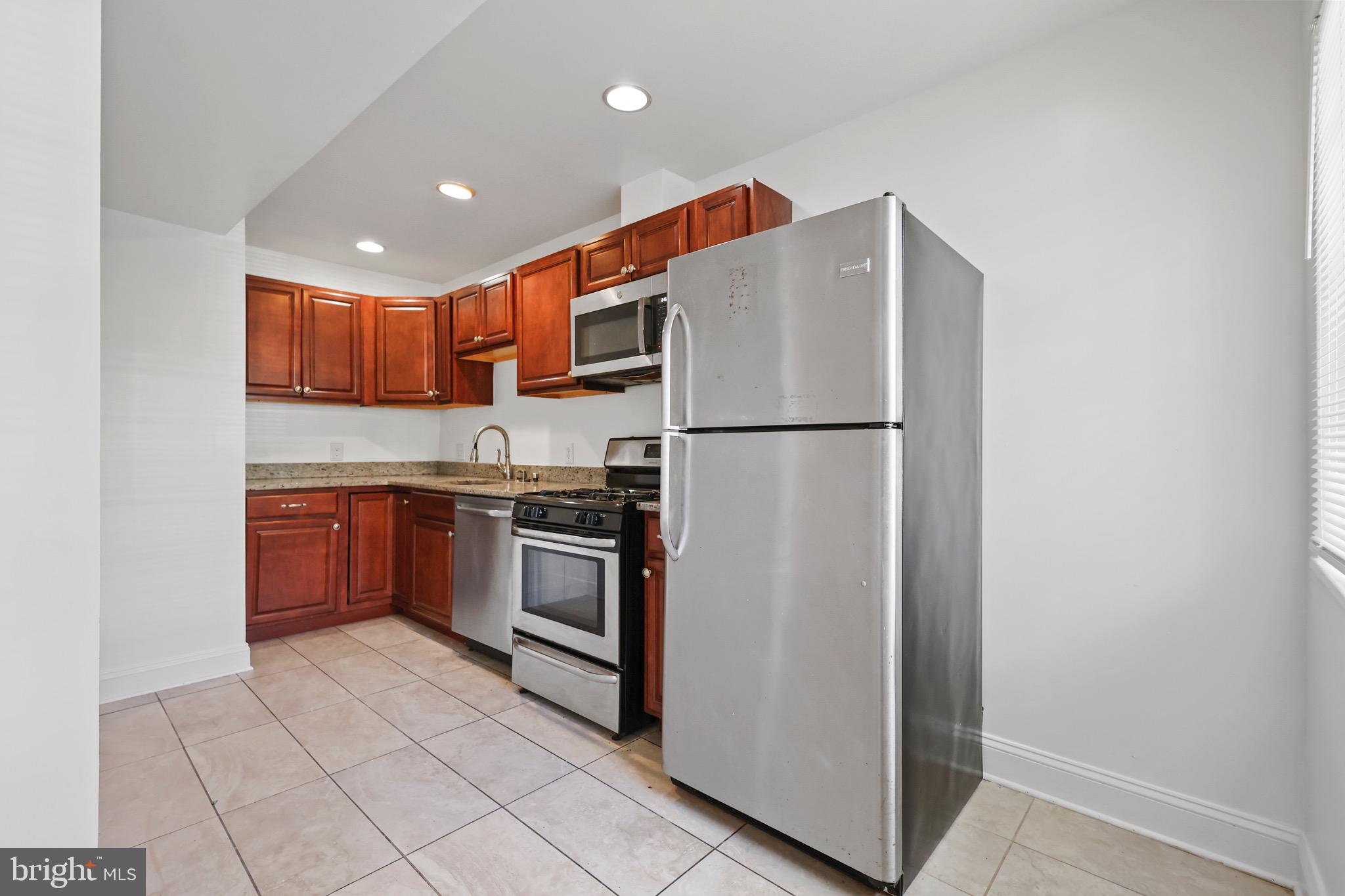 1316 Spring Road Northwest, Unit 102 Washington, DC 20010 - Photo 4 of 11 a kitchen with stainless steel appliances granite countertop a refrigerator sink and stove