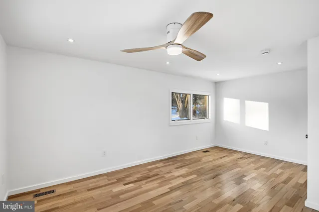 an empty room with a window and ceiling fan