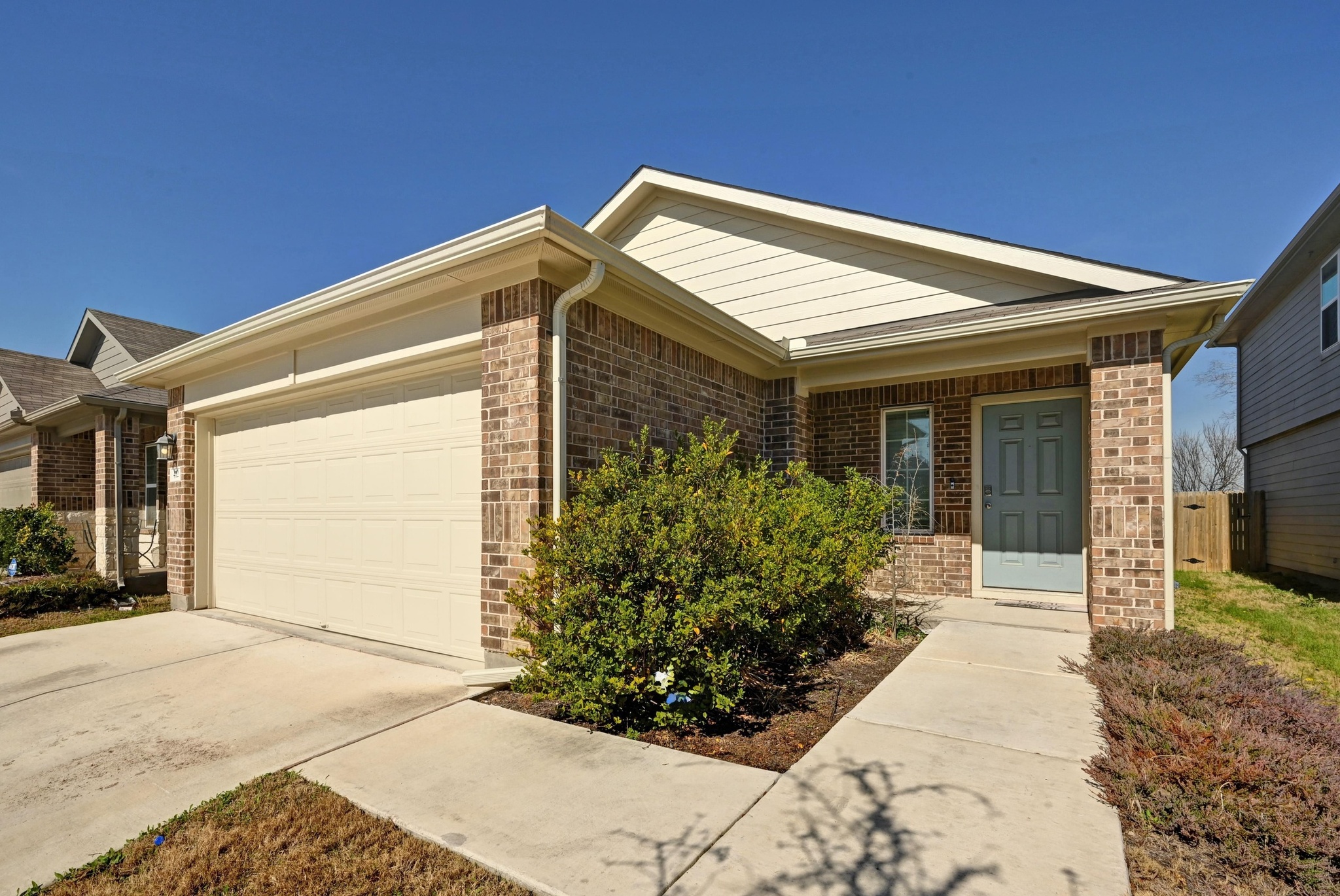 412 Sickle Loop Kyle, TX 78640 - Photo 2 of 25 Ranch-style home featuring a garage, driveway, brick siding, and covered porch