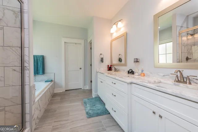 a spacious bathroom with double vanity a mirror a bathtub and shower