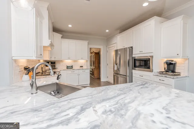 a kitchen with stainless steel appliances kitchen island granite countertop a refrigerator and a sink