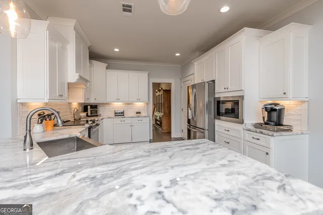 a large kitchen with kitchen island a stove a sink dishwasher a refrigerator and a microwave oven with white countertops