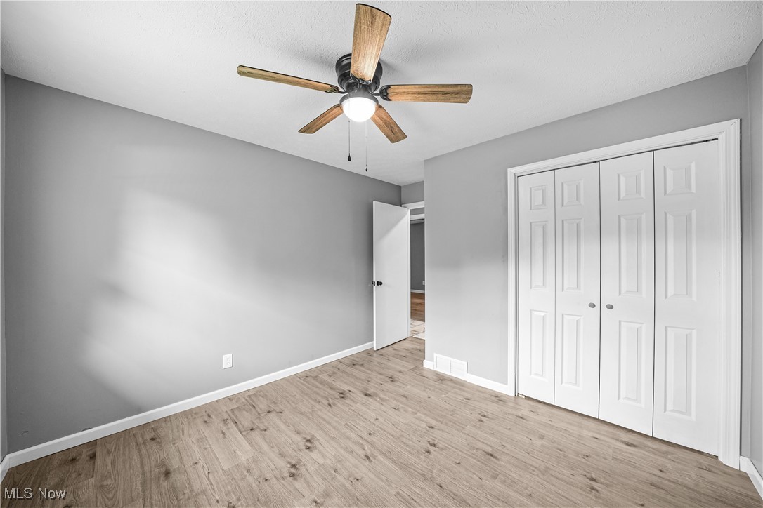 23595 Sandy Creek Road Minerva, OH 44657 - Photo 12 of 32 Unfurnished bedroom featuring wood finished floors, baseboards, a closet, and a ceiling fan