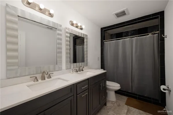 a bathroom with a double vanity sink toilet and mirror