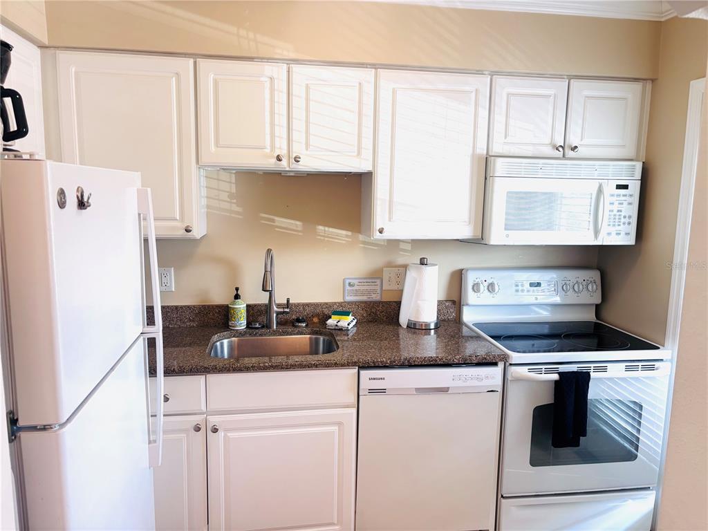 19417 Gulf Boulevard, Unit B209 Indian Rocks Beach, FL 33785 - Photo 8 of 24 a kitchen with stainless steel appliances granite countertop a sink stove and cabinets