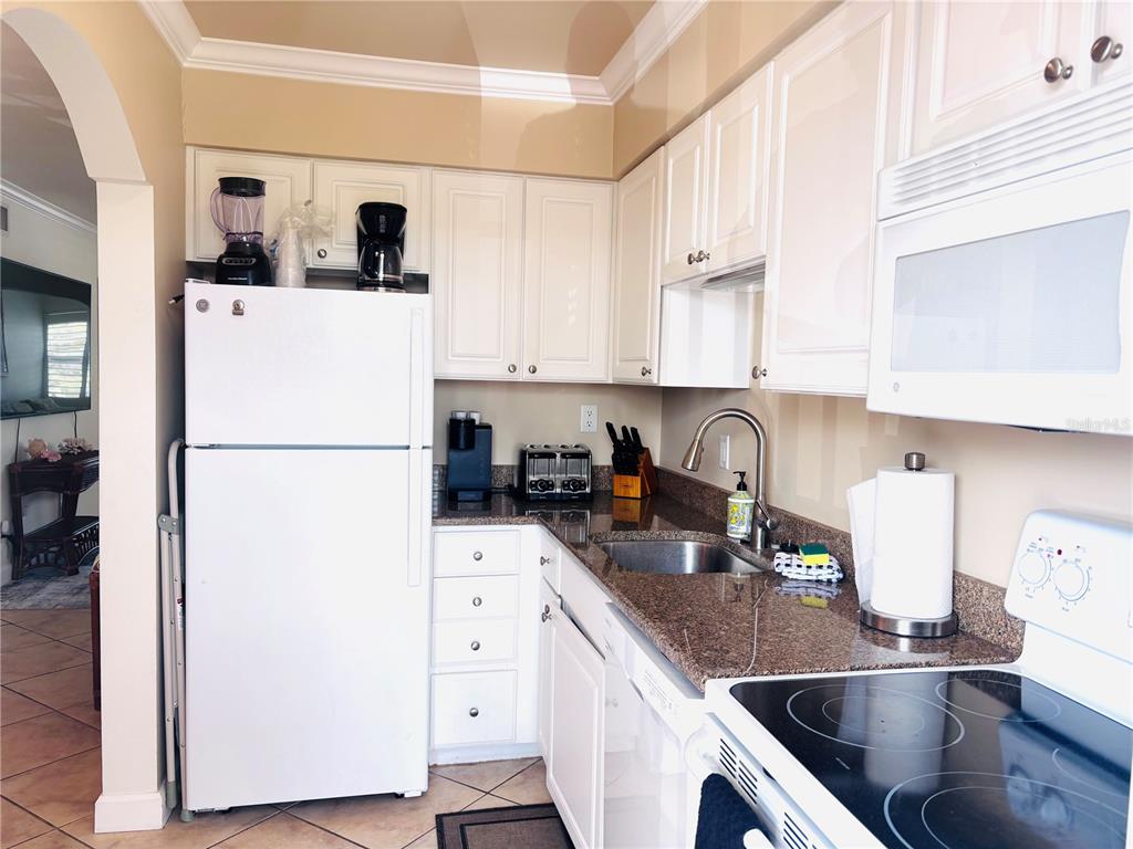 19417 Gulf Boulevard, Unit B209 Indian Rocks Beach, FL 33785 - Photo 9 of 24 a kitchen with a refrigerator a stove a sink a counter space and cabinets