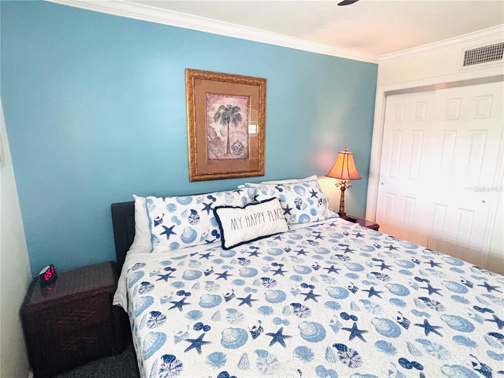 19417 Gulf Boulevard, Unit B209 Indian Rocks Beach, FL 33785 - Photo 10 of 24 a bedroom with a bed and a lamp on dresser