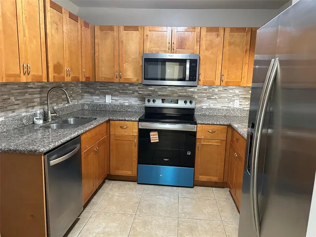 a kitchen with stainless steel appliances granite countertop a refrigerator a stove a sink and a microwave