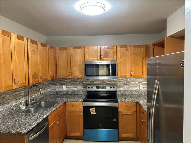 a kitchen with stainless steel appliances granite countertop a stove a sink and a microwave