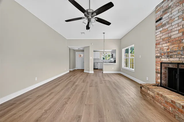 a view of an empty room with window and wooden floor