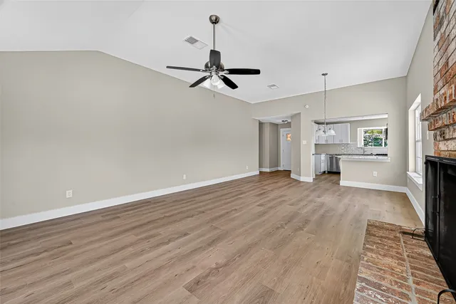 a view of an empty room with a window and wooden floor