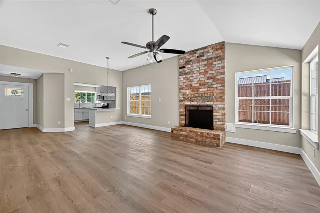 an empty room with windows and fireplace