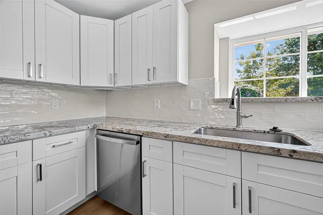 a kitchen with granite countertop white cabinets and sink