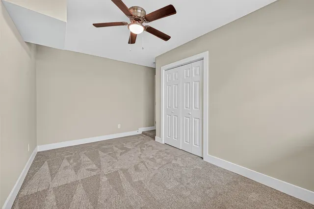 an empty room with closet and a ceiling fan