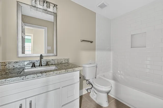 a bathroom with a granite countertop toilet a sink and a bathtub