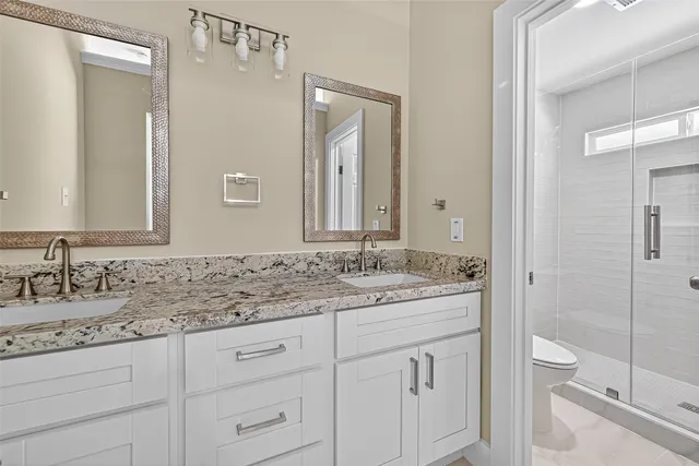 a bathroom with a granite countertop sink a toilet and a mirror