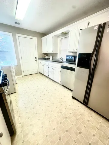a kitchen with granite countertop a sink a stove top oven and cabinetry
