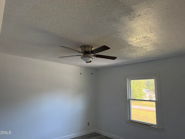 an empty room with a window and a fan