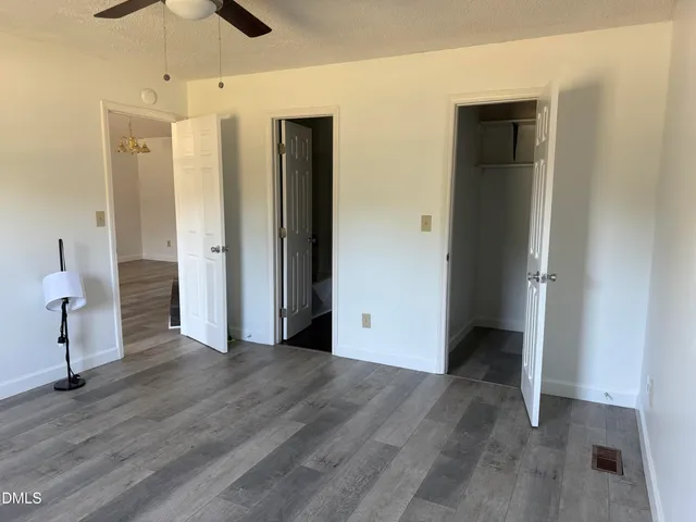 an empty room with wooden floor and a ceiling fan