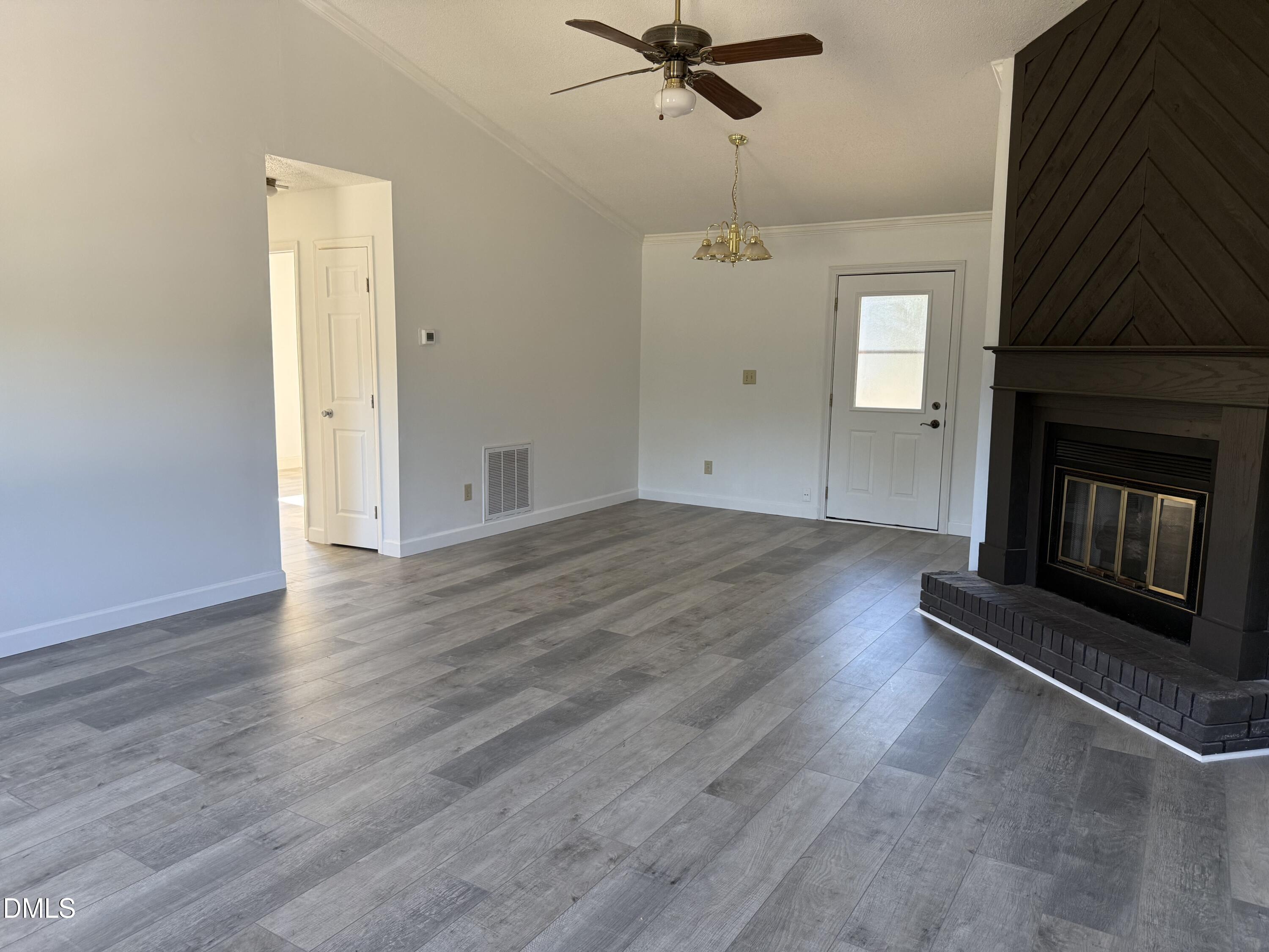 5509 Sandy Run Knightdale, NC 27545 - Photo 8 of 21 an empty room with wooden floor a ceiling fan and a fireplace