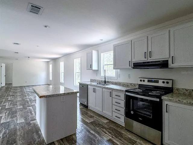 a kitchen with stainless steel appliances granite countertop a sink stove and cabinets