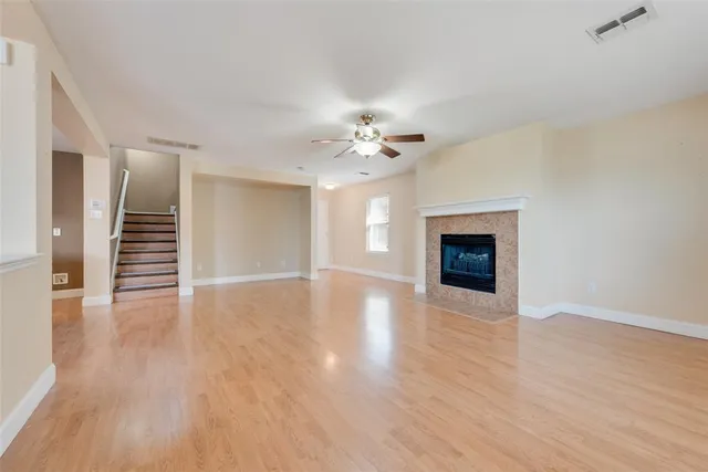 a view of an empty room with wooden floor and a fireplace