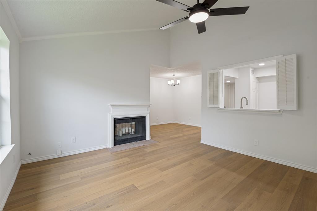 5300 Keller Springs Road, Unit 2042 Dallas, TX 75248 - Photo 8 of 28 Vaulted ceiling living space featuring light wood-finish flooring, a white mantel fireplace, and a ceiling fan