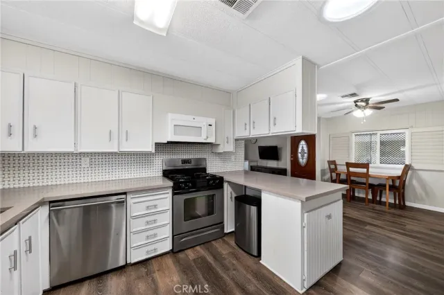 a kitchen with granite countertop a stove top oven a sink dishwasher and white cabinets with wooden floor