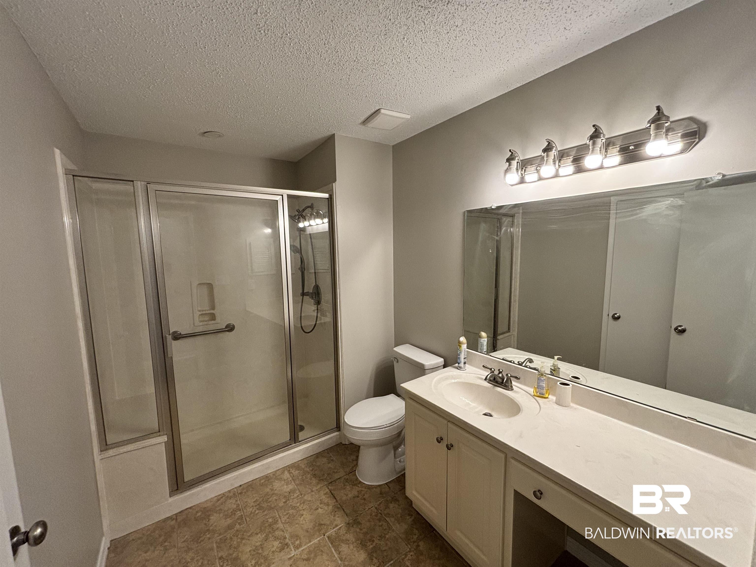 10 Soldiers Route Daphne, AL 36527 - Photo 16 of 26 Bathroom featuring a textured ceiling, vanity, a shower stall, and dark tile patterned flooring