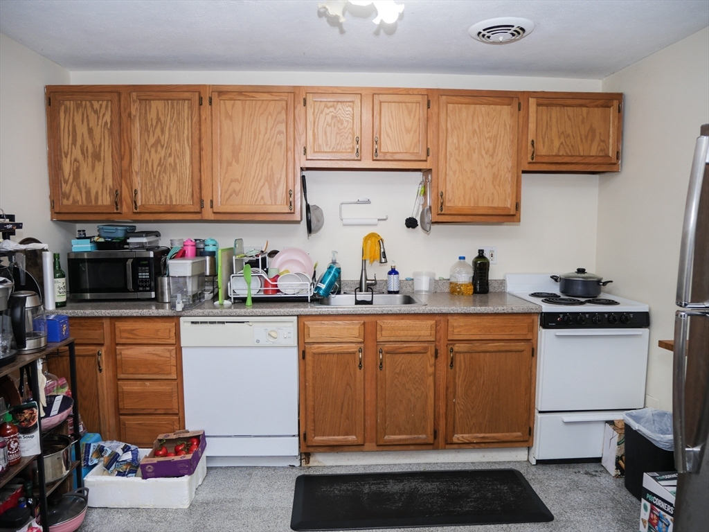 217 Kent Street, Unit 1 Brookline, MA 02446 - Photo 1 of 8 a kitchen with stainless steel appliances granite countertop a sink stove and cabinets