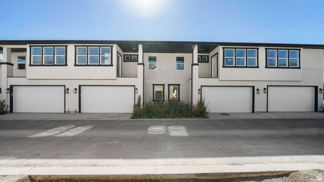729 South Harrison Drive West Springville, UT 84663 - Photo 22 of 36 Modern multi-unit building featuring a light-colored facade with dark trim, multiple attached garages, and individual balconies
