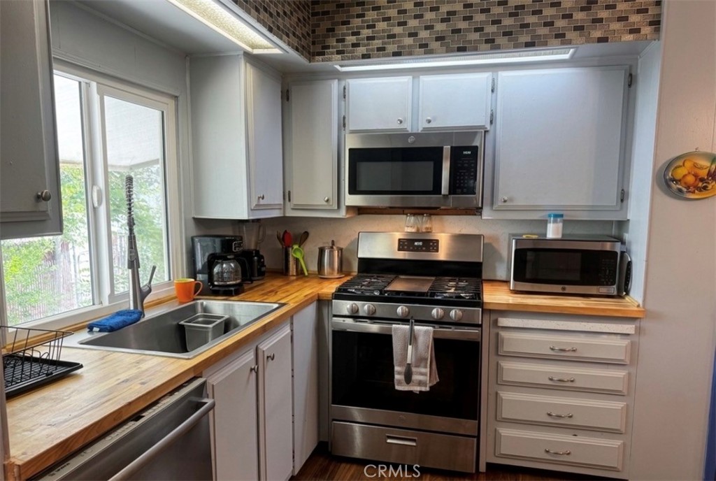 13870 Rodeo Drive Victorville, CA 92395 - Photo 7 of 22 a kitchen with granite countertop a stove top oven a sink a counter space and cabinets