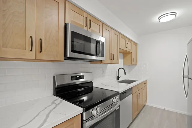 a kitchen with stainless steel appliances granite countertop a sink stove and microwave