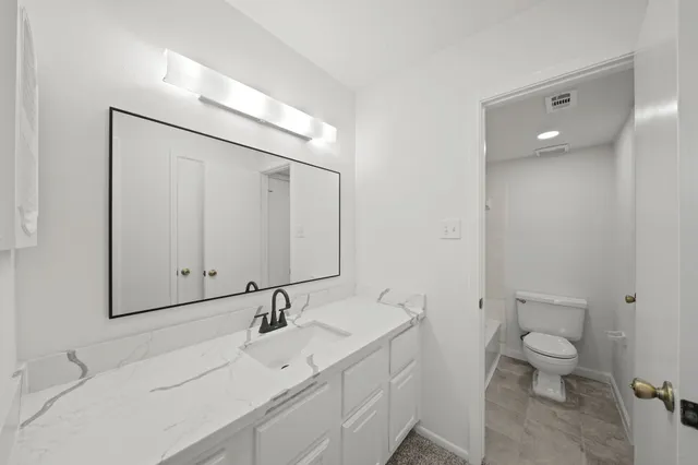 a bathroom with a sink and mirror with toilet