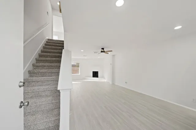 a view of an empty room with wooden floor and windows