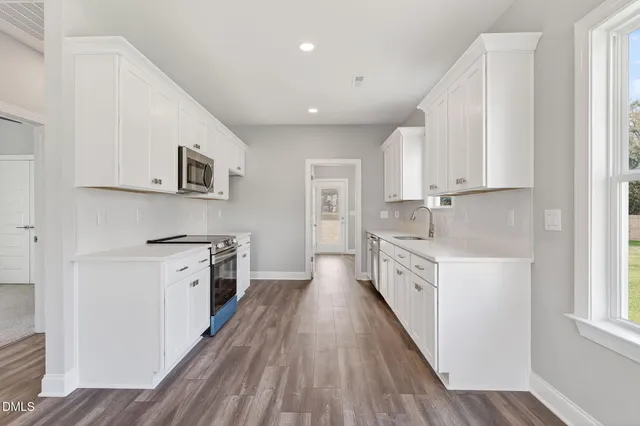a large kitchen with stainless steel appliances granite countertop a lot of counter space and wooden floor