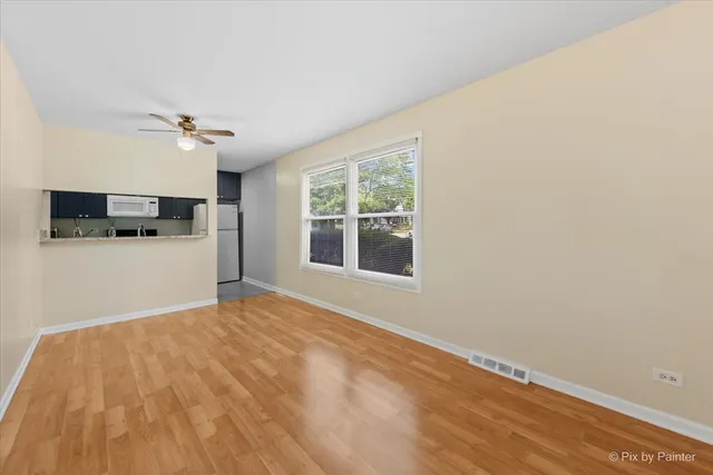 a view of a kitchen with wooden floor and a ceiling fan