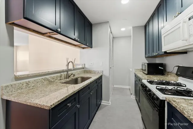 a kitchen with granite countertop stainless steel appliances a sink stove and cabinets