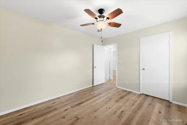 an empty room with wooden floor and a ceiling fan