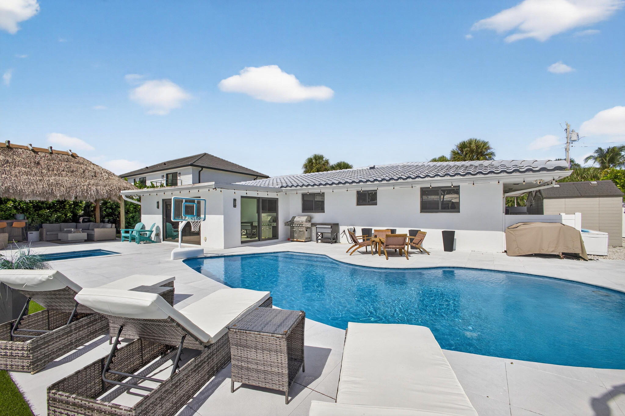 12 Leeward Circle Tequesta, FL 33469 - Photo 40 of 61 a view of a patio with couches table and chairs under an umbrella with large trees