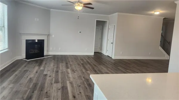 an empty room with wooden floor and fan