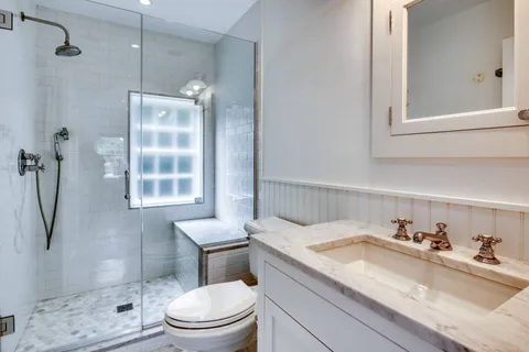 a bathroom with a granite countertop sink a toilet and shower