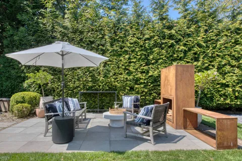 a view of a patio with couches table and chairs under an umbrella