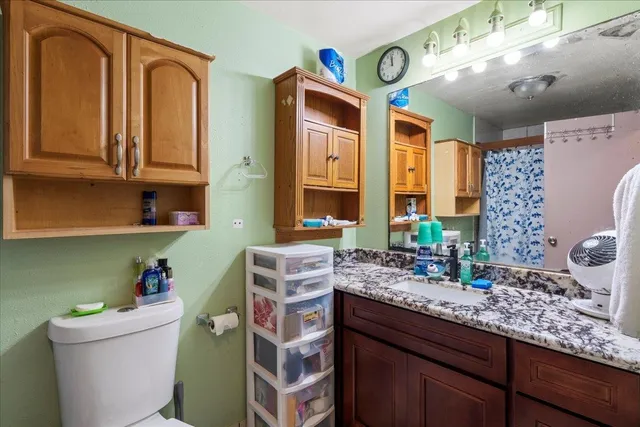 a bathroom with a granite countertop toilet sink and mirror