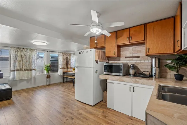 a kitchen with stainless steel appliances granite countertop a refrigerator a oven a sink dishwasher and white cabinets with wooden floor