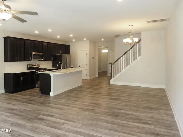 a open kitchen with kitchen island a sink dishwasher a refrigerator and a microwave oven with cabinets