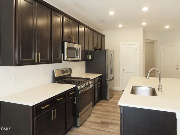 a kitchen with stainless steel appliances granite countertop a sink stove and refrigerator